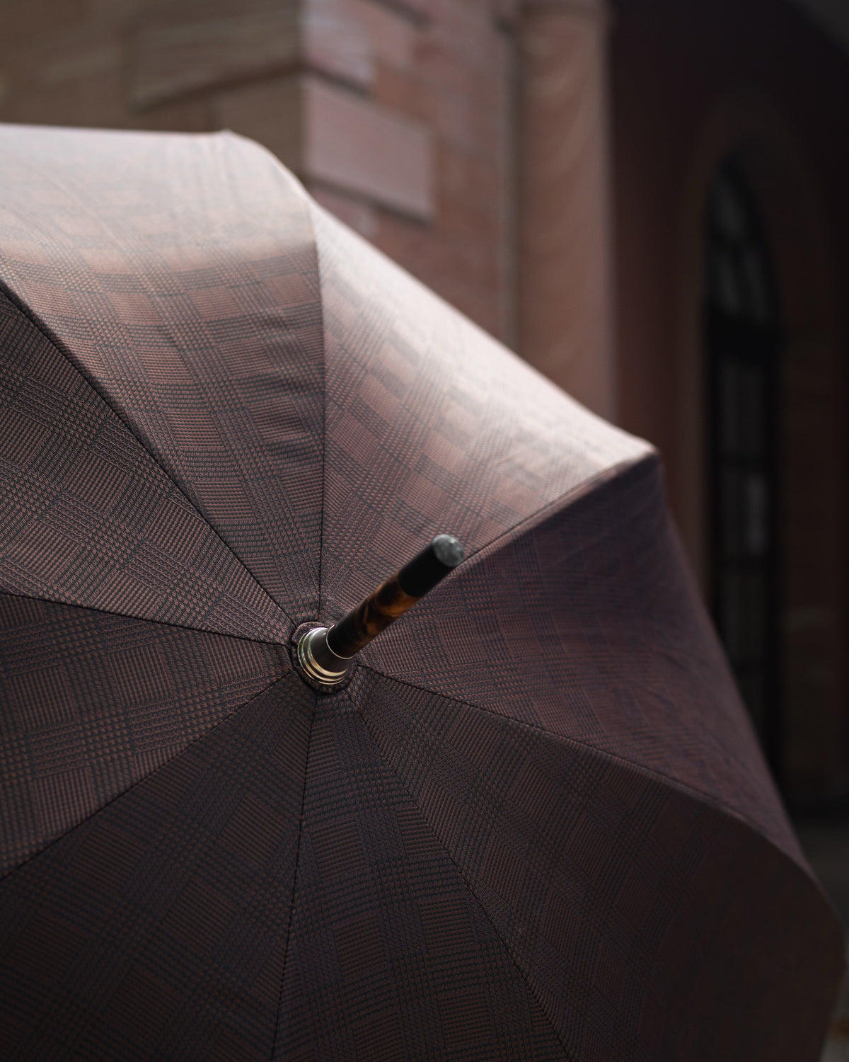 Woman walking through a rainy urban street carrying a large bright yellow umbrella