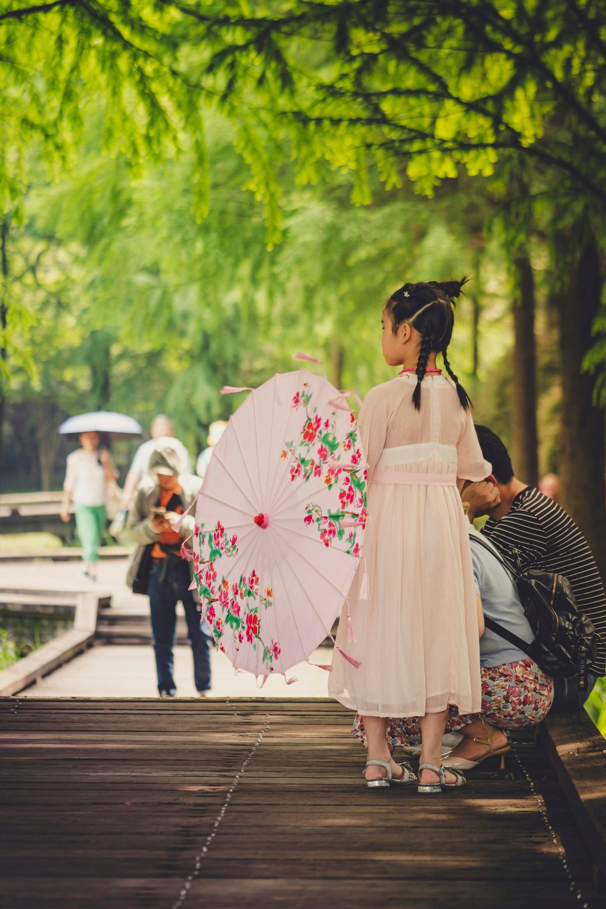 Woman in white dress using a parasol umbrella for sun protection while walking outdoors