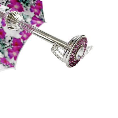 Silvered Ilmarchesato umbrella adorned with anemones and fuchsia crystals, showcasing a floral design against a rainy backdrop.
