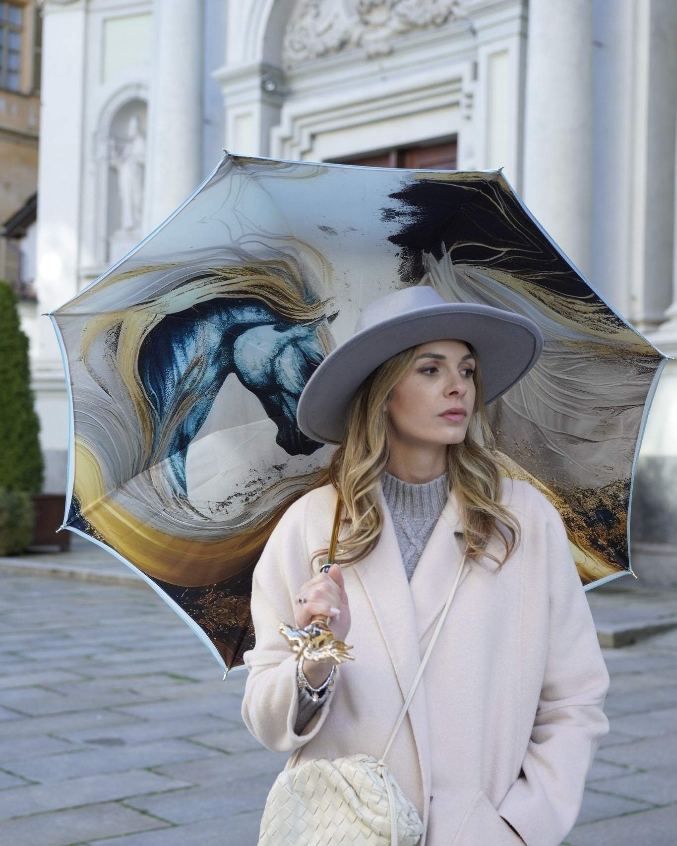 Light blue rain umbrella by Ilmarchesato with a gold horse handle and silk satin canopy, designed for elegant rain protection.