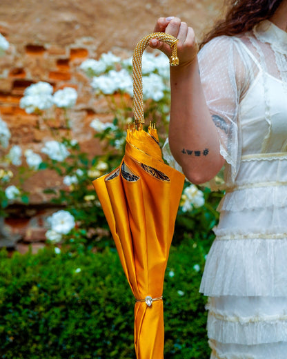 Golden satin rain umbrella by Ilmarchesato with double canopy, Swarovski crystals, and a 24K gold handle.