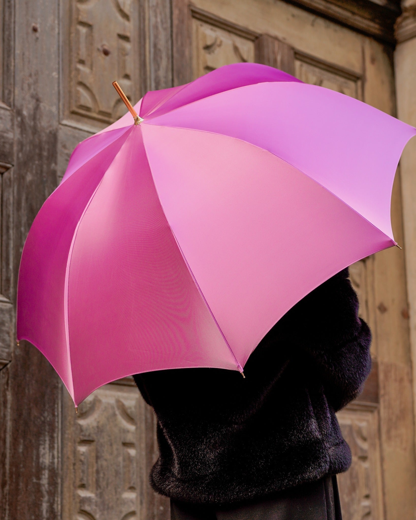 Luxury pink rain umbrella by Ilmarchesato with hand-painted floral handle and satin canopy, wind-resistant design.