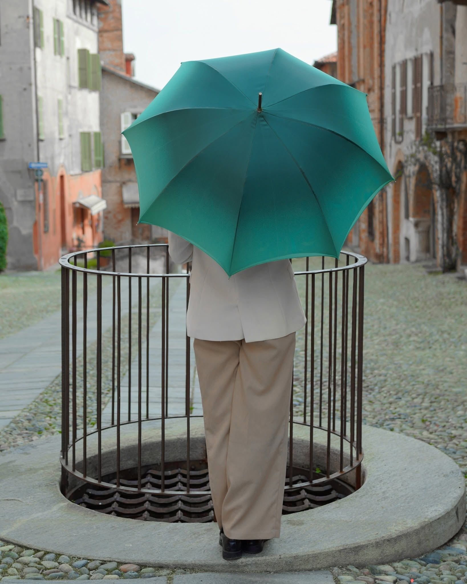 Luxury rain umbrella with peacock-inspired design and blue ostrich leather handle by Ilmarchesato, shown open with intricate patterns.
